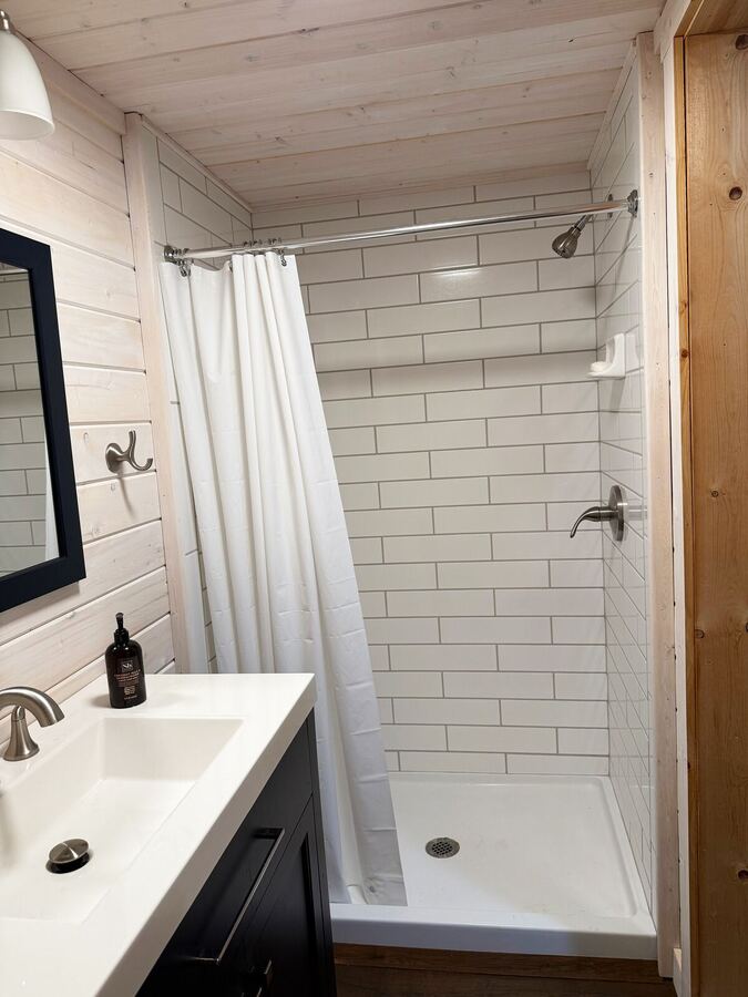 Bathroom with a white subway-tile shower and dark vanity