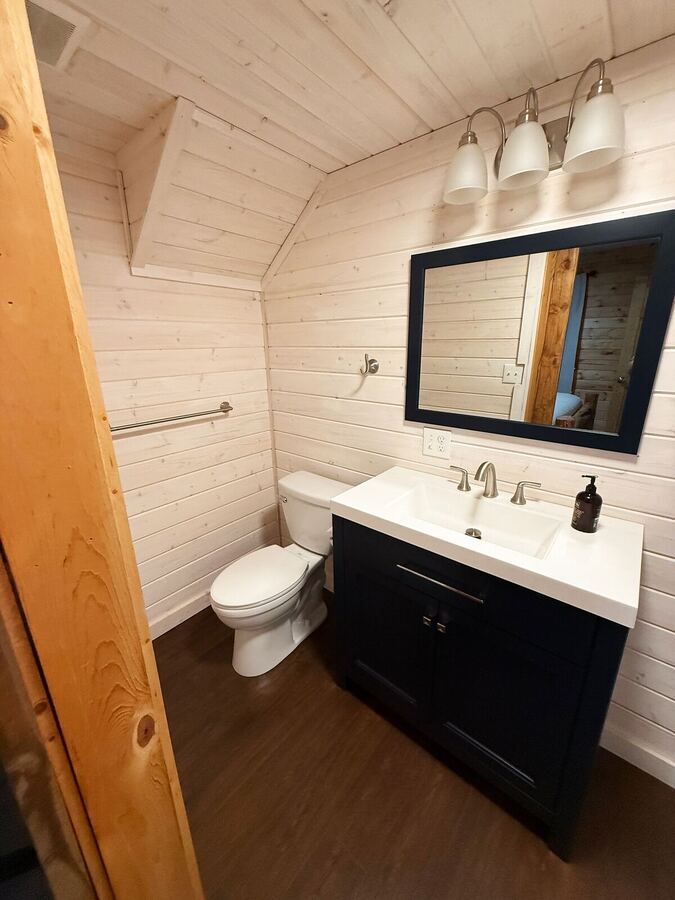 The same bathroom showing the dark vanity, mirror and white paneled walls