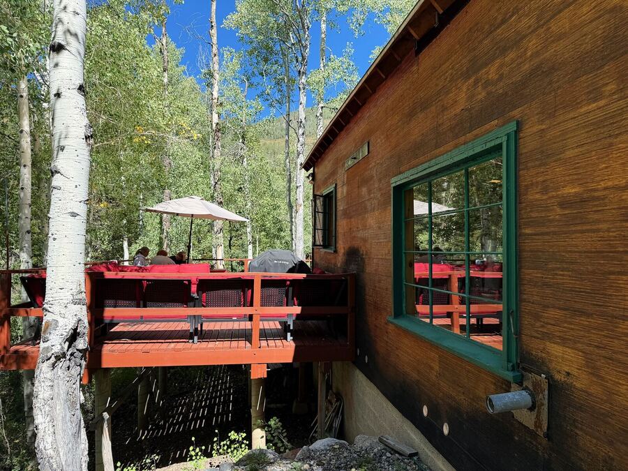 The elevated deck alongside the cabin, high among aspen trunks