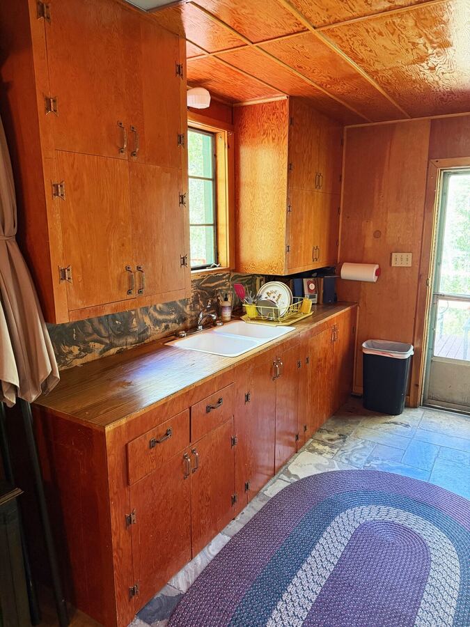 Kitchen counter and original wood cabinets with a window above the sink