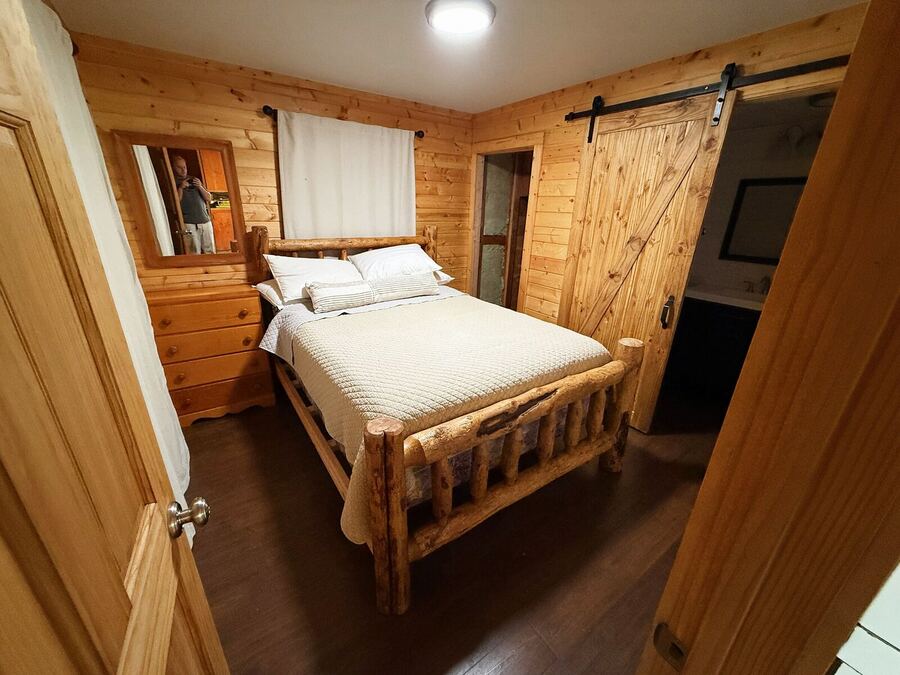Main bedroom with a log bed frame and a sliding barn door into the bath